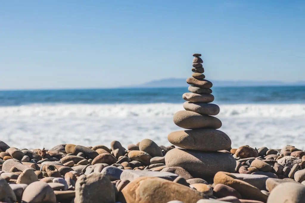 A group of stones balanced on top of one another by the ocean.